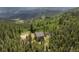 Mountain home surrounded by evergreen trees; stunning aerial view of the landscape at 1555 Three Peaks Rd, Golden, CO 80403