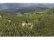 Exterior aerial of mountain home nestled in trees and on large lot at 1555 Three Peaks Rd, Golden, CO 80403