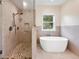 Elegant bathroom with stone-tiled walk-in shower and free-standing tub with views from the large window at 1555 Three Peaks Rd, Golden, CO 80403