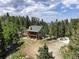 Mountain home aerial view surrounded by trees; deck, chimney, and green roof at 1555 Three Peaks Rd, Golden, CO 80403