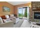 Inviting living room featuring a stone fireplace, a cozy sofa, and balcony access with scenic lake views at 1555 Three Peaks Rd, Golden, CO 80403