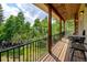 Covered porch with wood flooring and railings offering forest views and chairs for entertaining at 1555 Three Peaks Rd, Golden, CO 80403