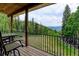 Open porch with wood flooring and railings offering mountain and forest views and chairs for entertaining at 1555 Three Peaks Rd, Golden, CO 80403