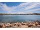 Scenic view of a lake with rock shoreline, trees along the horizon, and blue sky with light clouds at 7965 Lakeshore Dr, Parker, CO 80134