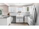 White kitchen boasts stainless steel appliances, granite countertops, a farmhouse sink, and white cabinets at 4280 S Pearl St, Englewood, CO 80113