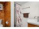 Cozy bathroom with wood paneling, featuring a shower with a floral curtain and a stylish sink at 6031 S Pennsylvania St, Centennial, CO 80121