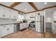Well-lit kitchen featuring white cabinets, stainless steel appliances, and a view of the staircase, blending style with functionality at 6031 S Pennsylvania St, Centennial, CO 80121