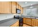 A close up of the kitchen with black appliances, light wood cabinets and neutral countertops at 22030 Hill Gail Way, Parker, CO 80138