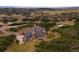 An aerial view of a unique castle-style home nestled in rolling hills with greenery and a pond at 3120 Bears Den Dr, Sedalia, CO 80135