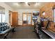 Bright exercise room with weights, treadmill, stationary bike, brick wall, and access to the outdoors at 3120 Bears Den Dr, Sedalia, CO 80135