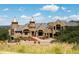 Majestic stone castle-like home with copper-topped turrets and a meticulously landscaped yard under a blue sky at 3120 Bears Den Dr, Sedalia, CO 80135