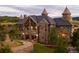 Stunning stone exterior of a castle-style home with a grand entrance, turrets, and lush landscaping at 3120 Bears Den Dr, Sedalia, CO 80135