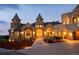 Grand stone home illuminated at dusk, featuring castle-like architecture and inviting, landscaped entryway at 3120 Bears Den Dr, Sedalia, CO 80135