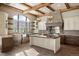 Well-lit kitchen with island, stainless appliances, custom cabinetry, breakfast bar, and wood-beamed ceiling at 3120 Bears Den Dr, Sedalia, CO 80135