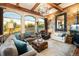 Inviting living room with large windows, stone walls, wood beams, comfortable seating, and natural light at 3120 Bears Den Dr, Sedalia, CO 80135