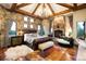 Main bedroom featuring a stone fireplace, wood beams, stone accents, and an ensuite bathroom at 3120 Bears Den Dr, Sedalia, CO 80135