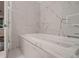 Close-up of a soaking tub in a luxe bathroom with marble tiling and a window view at 338 Saint Paul St, Denver, CO 80206