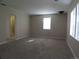 Spacious living room with neutral-colored walls, new carpet, and a doorway to the bathroom at 5660 Olive St, Commerce City, CO 80022