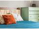 Close up of a beautifully made bed in a modern bedroom with colorful throw pillows and a rustic dresser at 4453 S Pagosa Way, Aurora, CO 80015