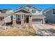 Charming two-story home featuring a covered porch with brick accents and a well-maintained front lawn at 11712 Lewiston St, Commerce City, CO 80022