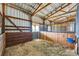 Interior stall in the barn, featuring wood paneling, hay bedding, and metal bars at 3487 Willownook Ranch Trl, Elizabeth, CO 80107