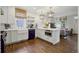 Bright eat-in kitchen with white cabinets, a farmhouse sink, an island, hardwood floors, and stainless steel appliances at 4508 Lowell Blvd, Denver, CO 80211