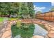 Backyard fish pond featuring stone accents, unique statues, and decorative landscaping near a wooden fence at 3 Glenview Dr, Littleton, CO 80123