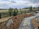 Landscaped backyard with a fire pit and rock garden along a walking path that borders a black rail fence at 23696 E Del Norte Pl, Aurora, CO 80016