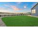 Large backyard features a green lawn, perimeter rock bed, and a black fence against an open landscape at 23696 E Del Norte Pl, Aurora, CO 80016