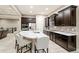 Modern kitchen features dark wood cabinetry, stainless appliances, large island with seating, and stylish tile backsplash at 23696 E Del Norte Pl, Aurora, CO 80016