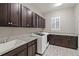This laundry room features dark cabinets, granite countertops, a stainless steel sink and a modern washing machine at 23696 E Del Norte Pl, Aurora, CO 80016