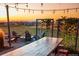 Relaxing outdoor seating area with a rustic wooden table, string lights, and a cozy fire pit overlooking a scenic landscape at 23696 E Del Norte Pl, Aurora, CO 80016