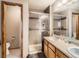 Bright bathroom featuring a tiled shower with glass door and double sinks with wood cabinets at 11395 E 116Th Dr, Commerce City, CO 80640