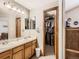 Bathroom with double sink vanity, large mirror, and walk-in closet with wood door at 11395 E 116Th Dr, Commerce City, CO 80640