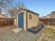Backyard shed with a blue door and landscaping, adding character and functionality to the property at 11395 E 116Th Dr, Commerce City, CO 80640