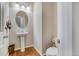 Bright powder room featuring a pedestal sink, an oval mirror, and wood floors at 3810 Cadence Dr, Castle Rock, CO 80109