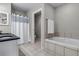 Bright bathroom featuring double sink vanity, tile flooring, and a soaking tub with tile surround at 35427 Welch Trl, Elizabeth, CO 80107