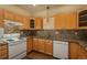 Well-lit kitchen featuring wooden cabinets, mosaic tile backsplash, and granite countertops at 2896 W Riverwalk Cir # 204, Littleton, CO 80123