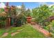 Landscaped backyard with a lush lawn, stone pathway, and mature plants at 1215 Jackson St, Denver, CO 80206