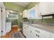 Charming kitchen with green walls, white cabinets, stainless steel appliances, and hardwood floors at 1215 Jackson St, Denver, CO 80206