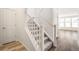 Staircase featuring carpeted steps, white banister, and neutral decor with view to beautiful wood floors beyond at 1889 Water Birch Way, Castle Rock, CO 80108