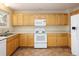 Functional kitchen with tile flooring, light wood cabinets, white appliances, and ample counter space at 4860 W 125Th Ave, Broomfield, CO 80020
