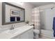 Bright bathroom with a decorative mirror, white cabinets, and shower with a patterned curtain at 2181 E Phillips Ln, Centennial, CO 80122
