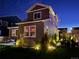 Backyard of two-story house exterior featuring landscaping with illuminated bushes at night at 1135 Basalt Ridge Loop, Castle Rock, CO 80108