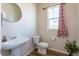 Stylish powder room with modern fixtures, pedestal sink, decorative mirror, and wood-look flooring at 1135 Basalt Ridge Loop, Castle Rock, CO 80108
