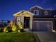 Two-story house exterior at night with stone accents, lights, and well-manicured lawn at 1135 Basalt Ridge Loop, Castle Rock, CO 80108