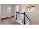 Bright carpeted hallway featuring staircase with decorative railing and natural lighting at 25126 E Bayaud Pl, Aurora, CO 80018