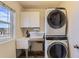 Convenient laundry room features a sink, cabinets, and stacked washer and dryer at 25126 E Bayaud Pl, Aurora, CO 80018