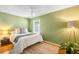 Cozy bedroom featuring green walls, hardwood floors, and a plush white bed with a window view at 4616 E Yale Ave, Denver, CO 80222