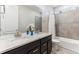 Well-lit bathroom featuring dual sinks, granite countertops, and a shower with a tub at 8099 Arapahoe Peak St, Littleton, CO 80125